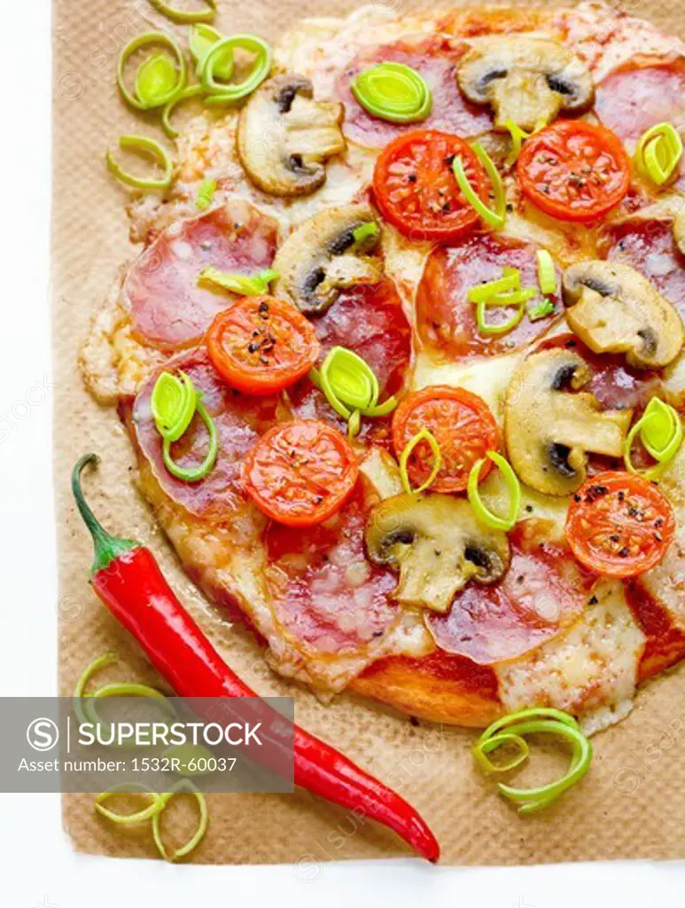 Pizza with salami, mushrooms, tomatoes, leek, mozzarella and chillis