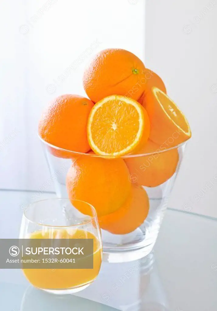 A glass of orange juice and fresh oranges