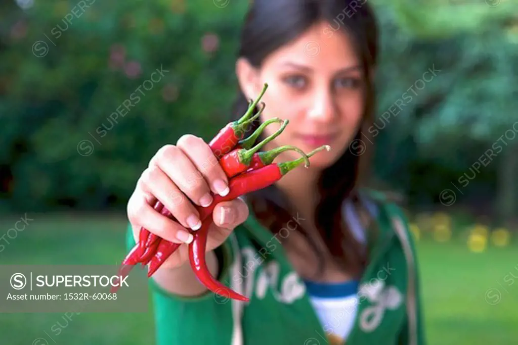 A woman holding fresh red chilli peppers