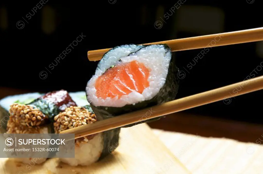 Maki sushi with salmon held in chopsticks