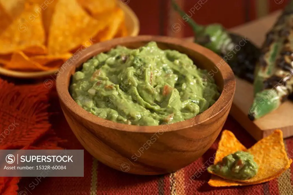 Guacamole in a Wooden Bowl; Tortilla Chips; Charred Jalapeno Peppers
