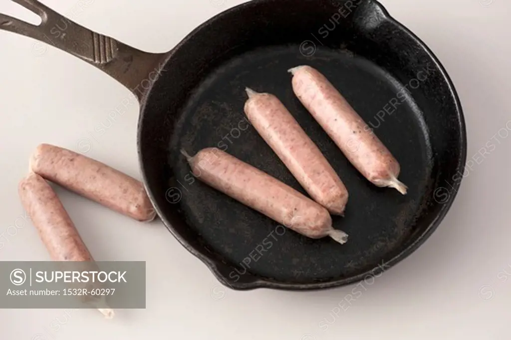 Uncooked Sausage in and Beside a Cast Iron Skillet