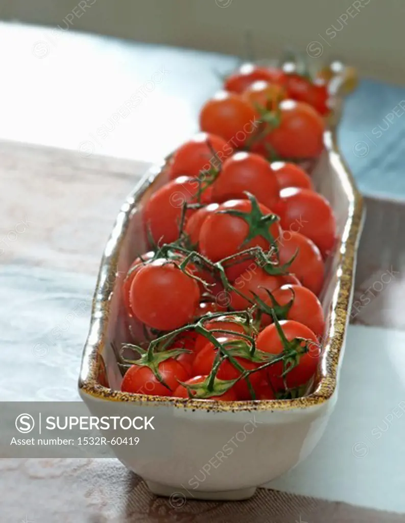 Tomatoes (still on the stem) in a ceramic dish