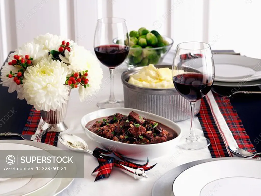 Saddle of venison, mashed potatoes and Brussels sprouts on a table decorated for Christmas