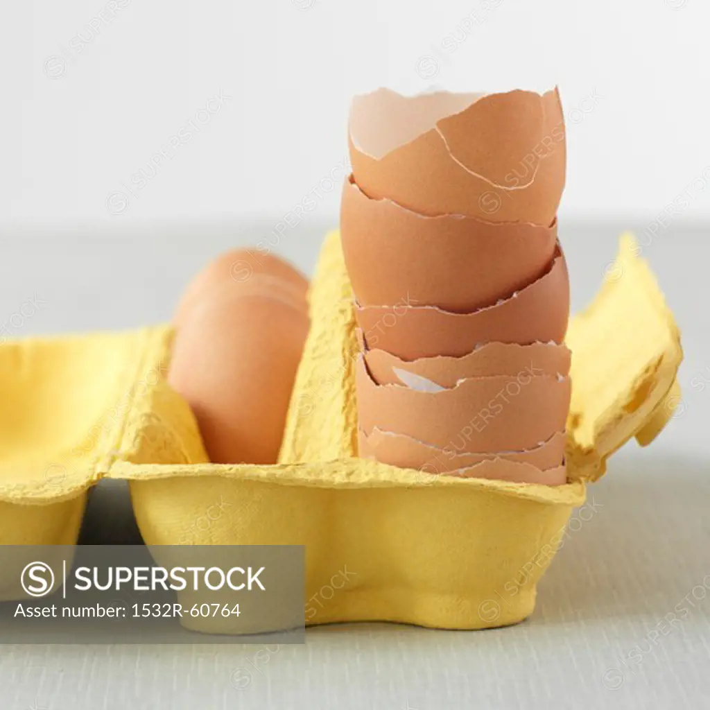 A stack of egg shells in a yellow egg box