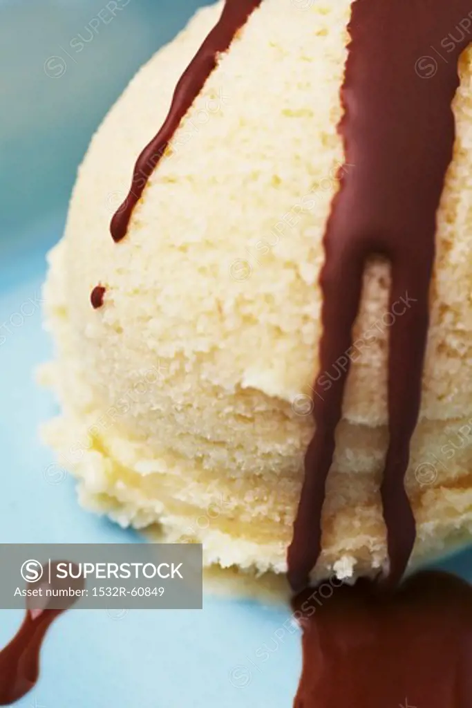 A scoop of vanilla ice cream with chocolate sauce (close-up)