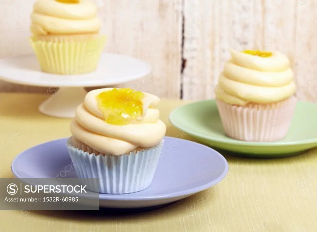 Frosted Cupcakes with Lemon Curd; On Blue, Green and White Plates