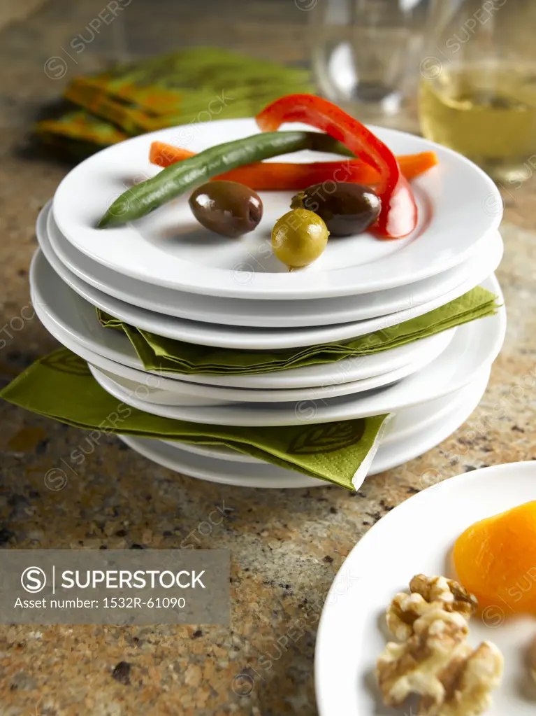 Stacks of White Plates; Some with Healthy Munchies; Veggies, Olives and Nuts