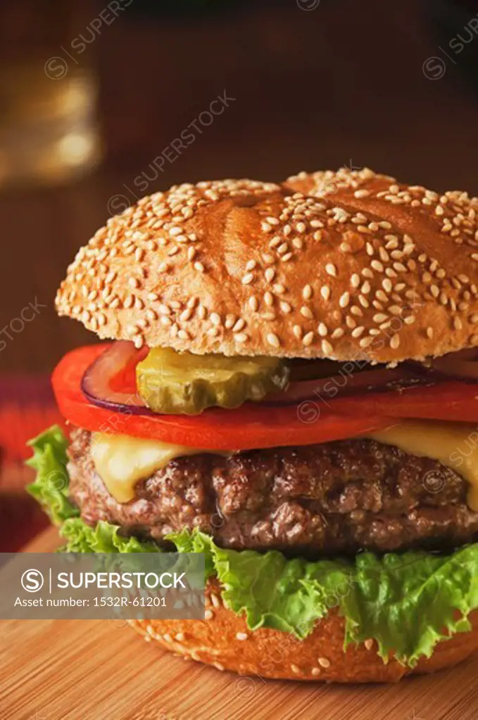 Juicy Cheeseburger with Tomato, Onion and Pickle on Sesame Seed Bun