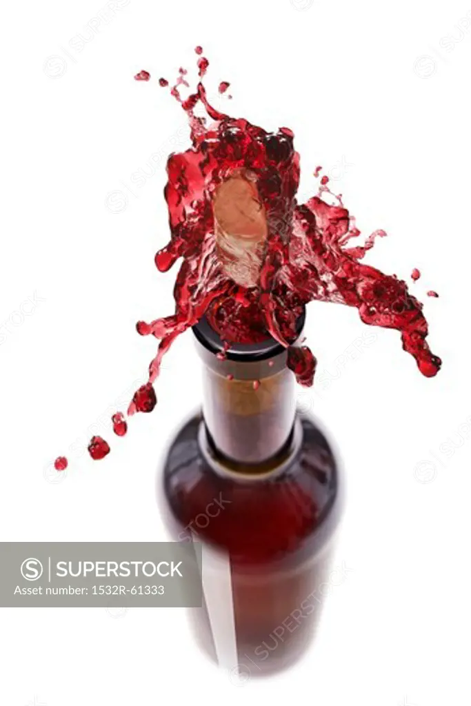 Red wine spraying out of a bottle