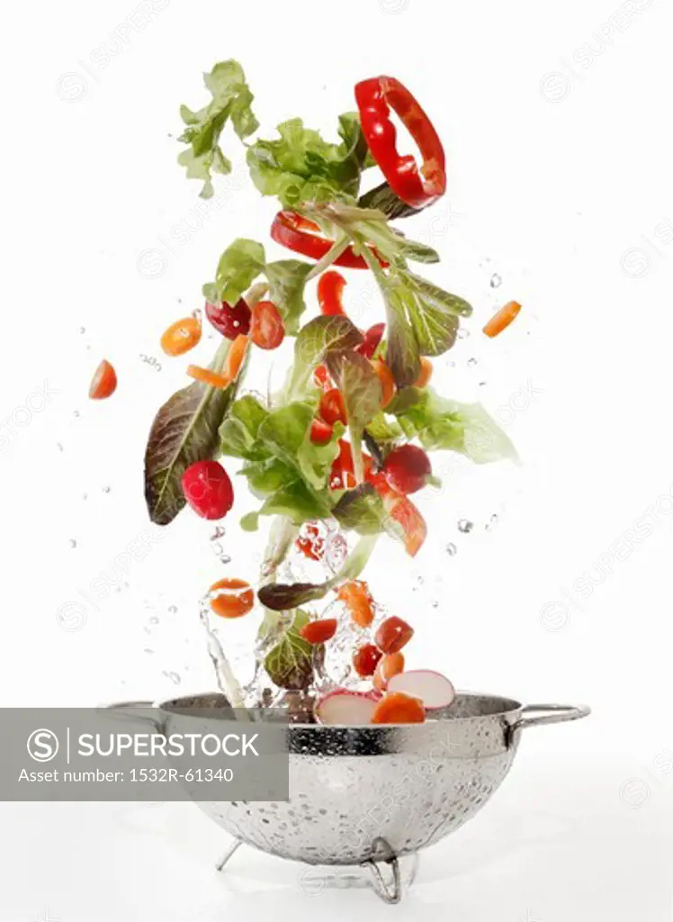 Salad ingredients being washed in a colander