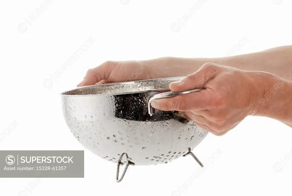 Hands holding a dripping colander