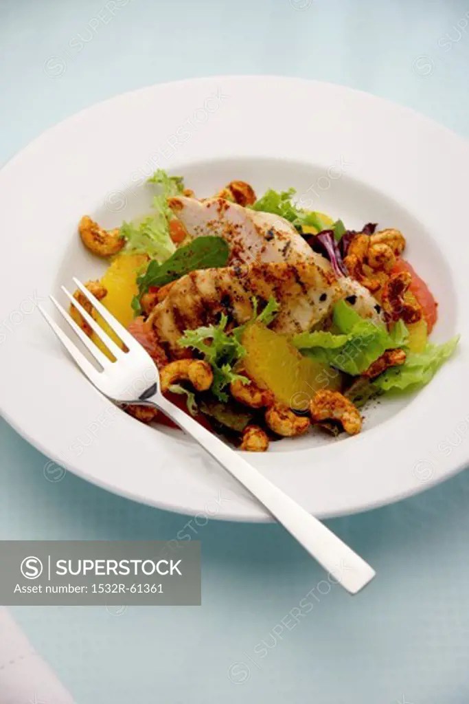 Grilled chicken fillers with citrus fruits, lettuce and cashew nuts
