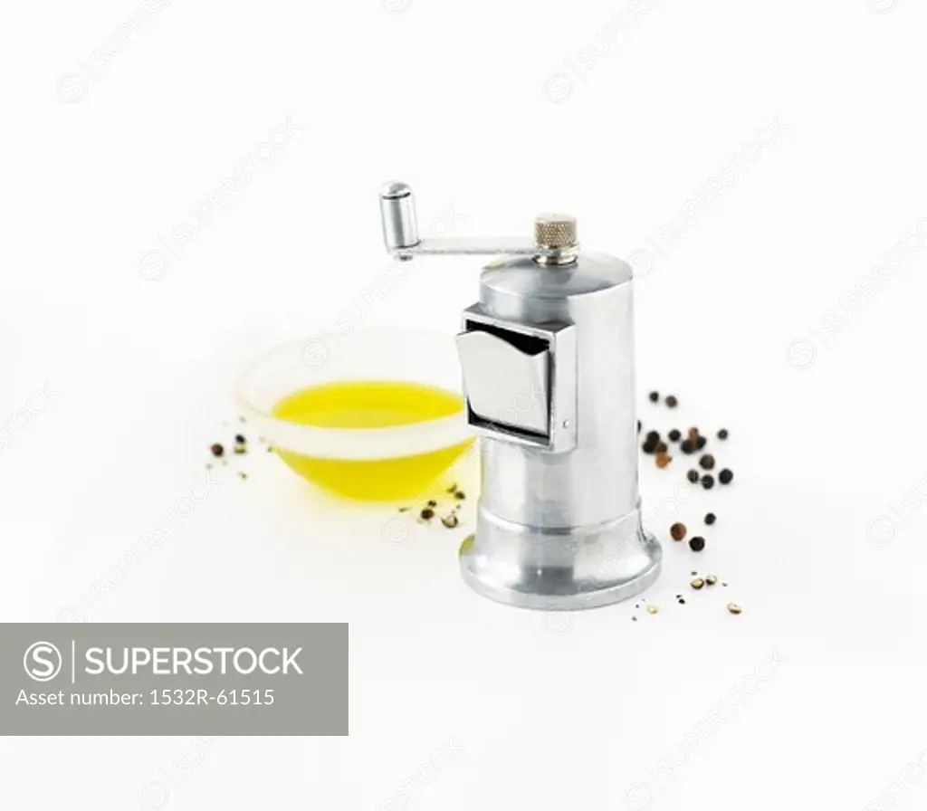 Pepper grinder, peppercorns and olive oil