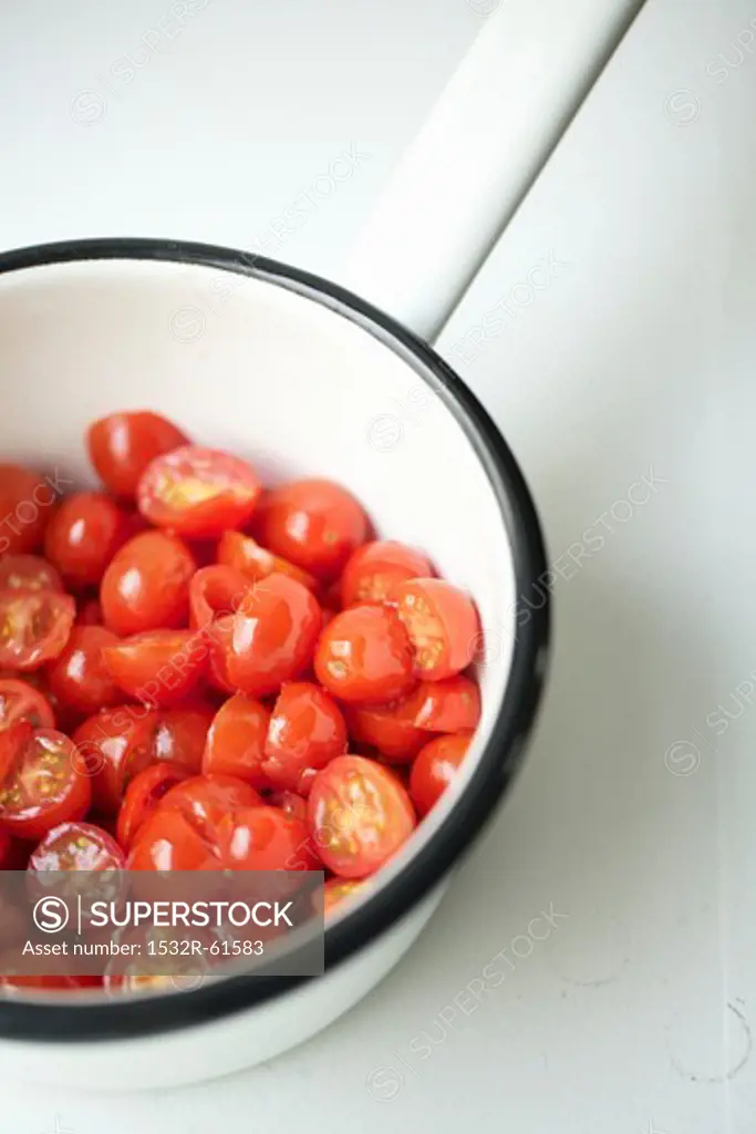 Sliced Cherry Tomatoes in a White Pot with Black Rim; From Above