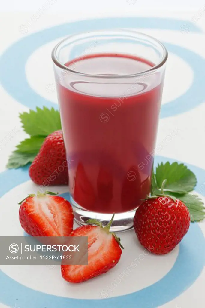 A jar of strawberry smoothie and fresh strawberries