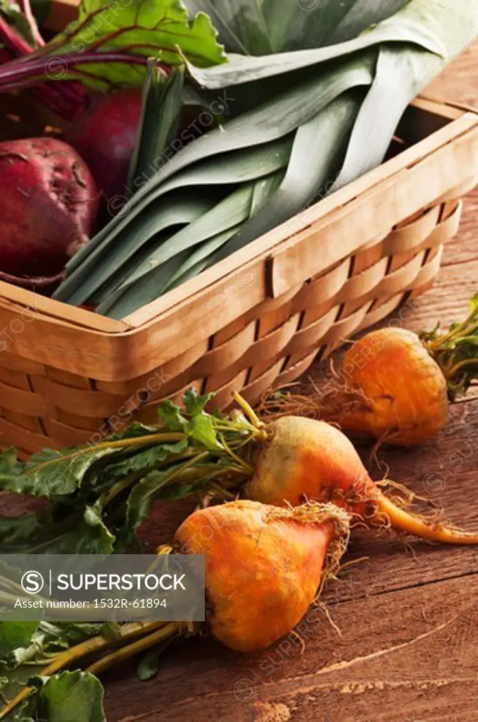 Organic Golden Beets Next to a Basket Filled with Red Beets and Leeks
