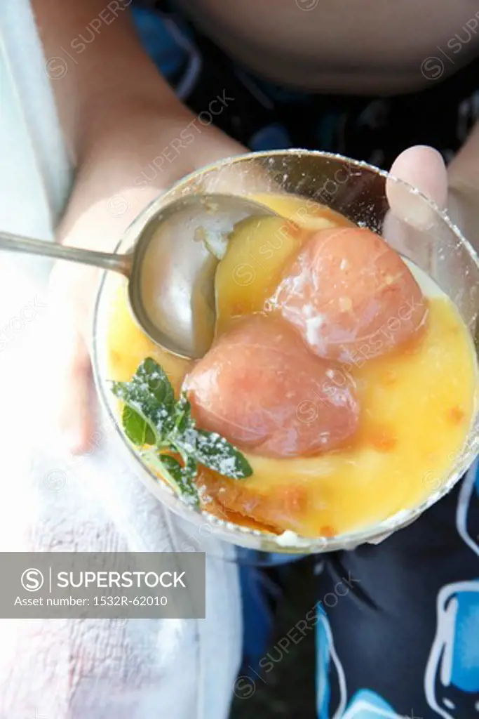Hands holding a bowl of Crimpolene Pudding (vanilla pudding with tinned fruit)