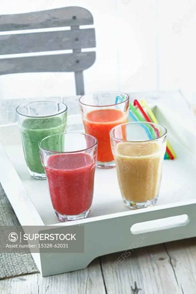 Four smoothies on a tray on a wooden table