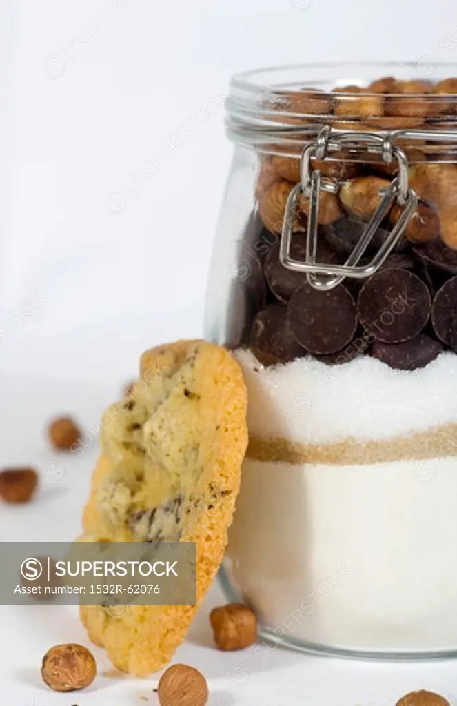 A hazelnut biscuit next to a jar of ingredients