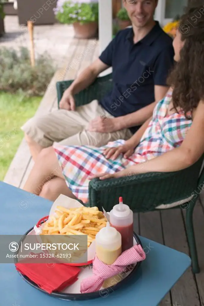 Couple sitting on terrace, chips in foreground