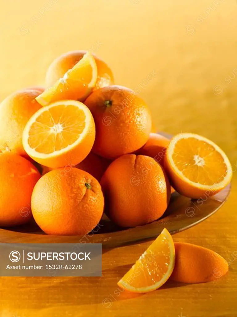 Oranges, whole and halved, in a wooden bowl
