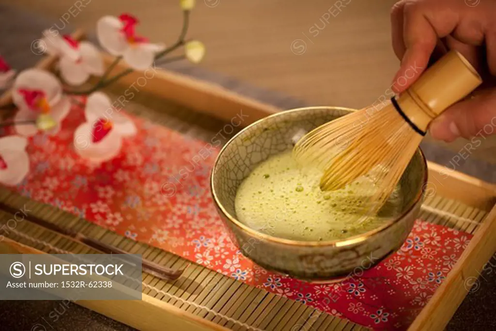 Mixing Japanese Matcha Green Tea in a Ceremonial Bowl with Whisk