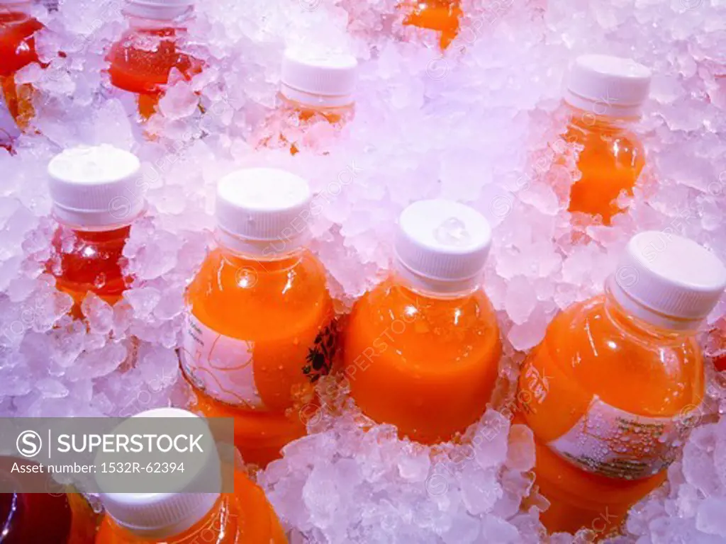 Bottles of freshly pressed fruit juice on ice