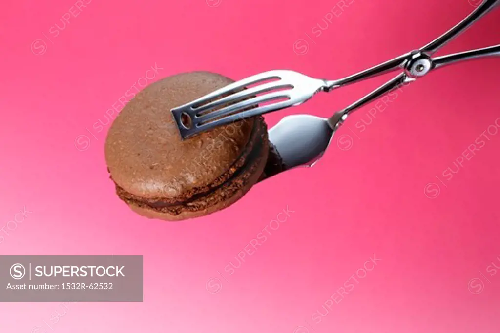 Cake tongs holding a chocolate macaroon