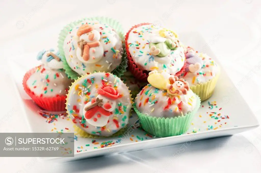 Muffins with icing, colourful sprinkles and sugar ornaments
