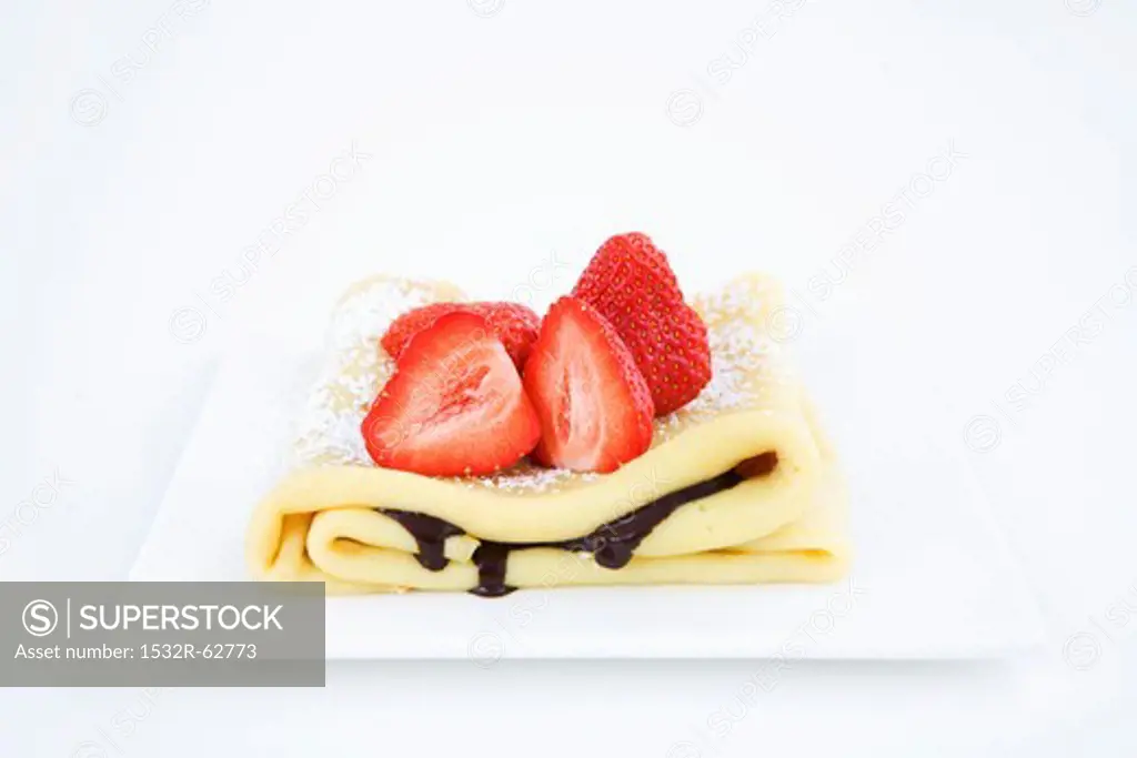 A pancake with chocolate sauce and fresh strawberries