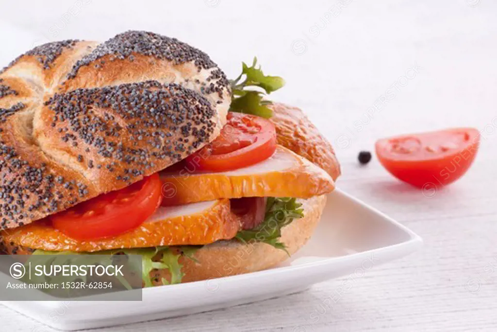 A chicken breast and tomato sandwich on a poppyseed roll