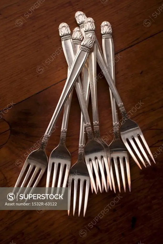 Many Silver Forks on a Wooden Table
