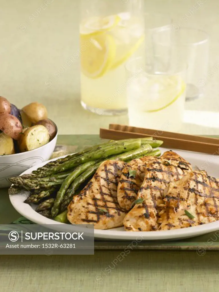 Grilled Chicken Breasts with Asparagus on a Serving Dish; Potatoes and Lemonade