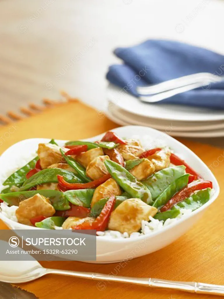 Chicken Stir Fry with Snow Peas and Red Peppers Over Rice in a Serving Bowl