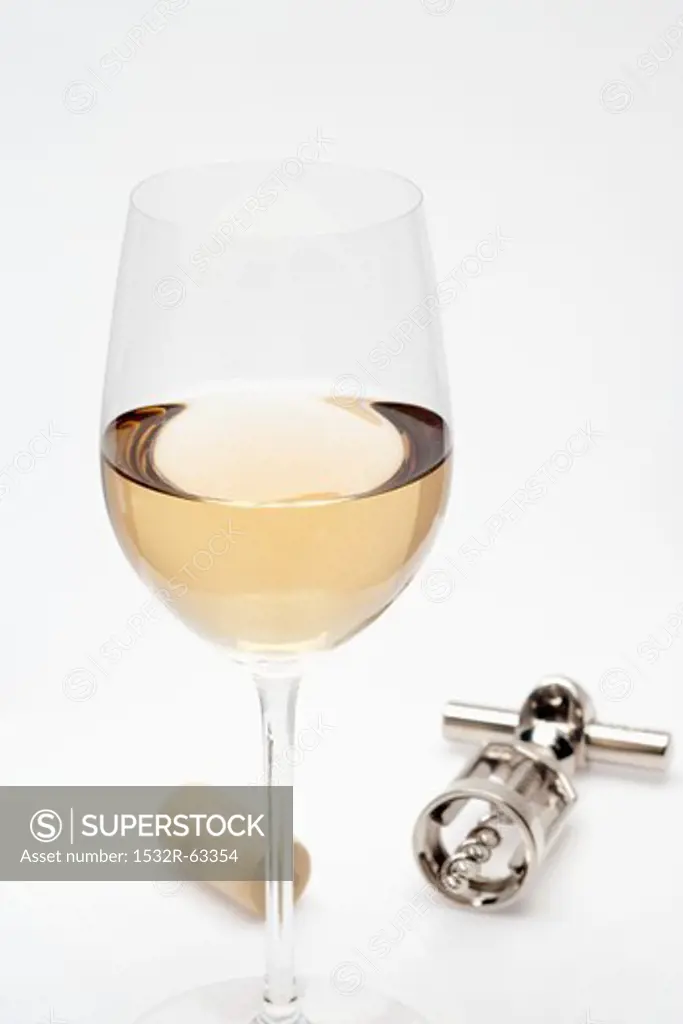 Glass of white wine, cork and corkscrew