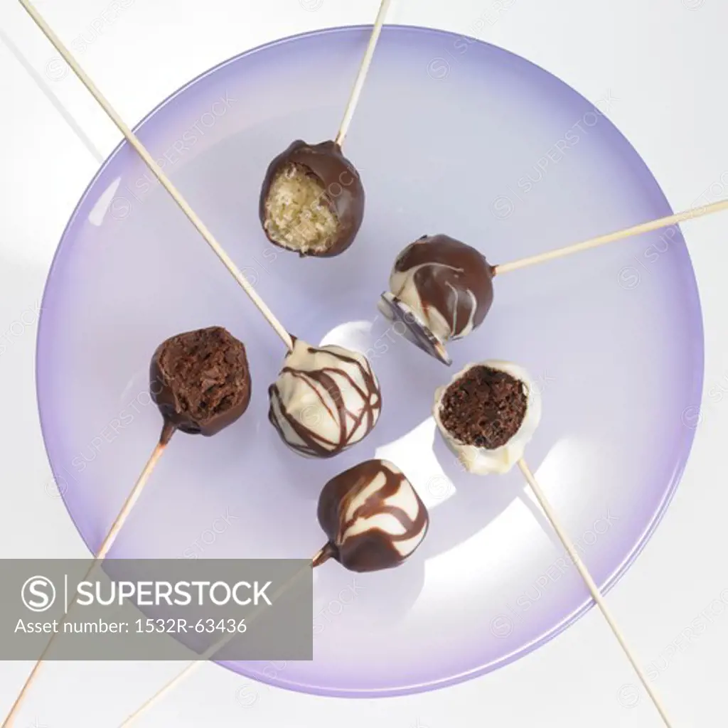 Cake pops with chocolate icing, one with a bite taken out