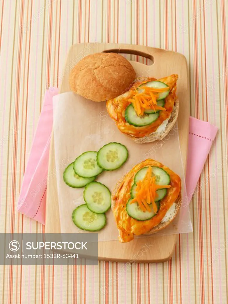 A chicken sandwich with cucumber and carrots