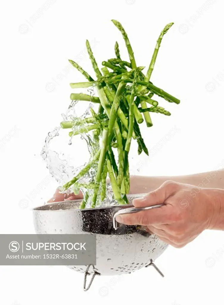 Washing green asparagus in a colander