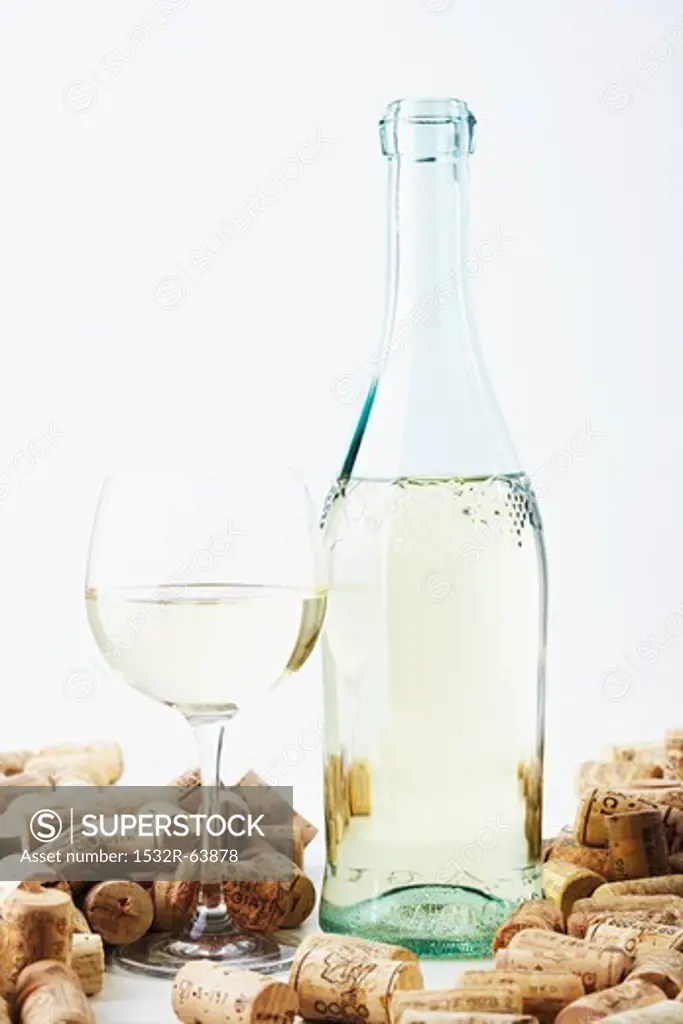 A bottle and a glass of wine with corks