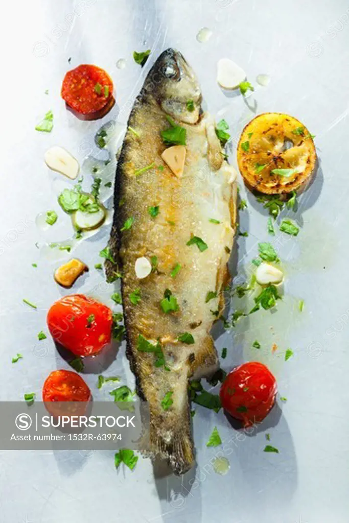 Fried trout with herbs, garlic, tomatoes and lemons