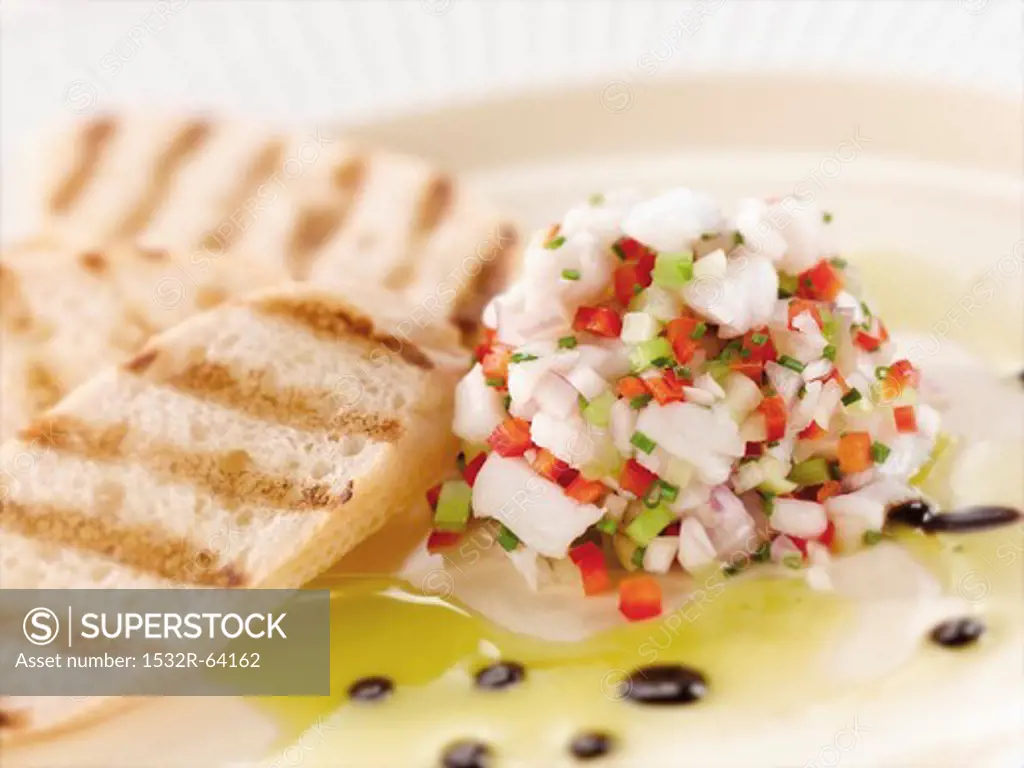 Citrus Ceviche of Bass Fish with Grilled Bread on a White Plate