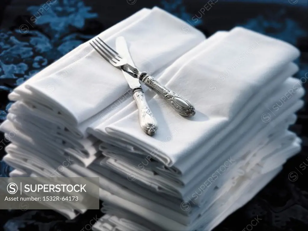 Two Stacks of White Cloth Napkins with a Fork and Knife