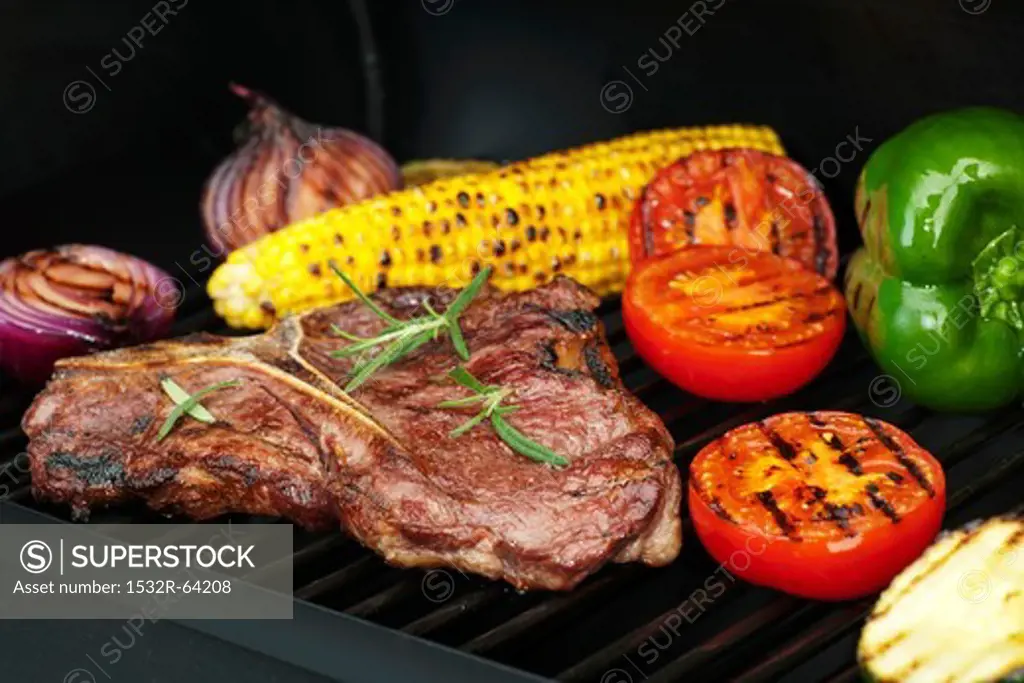 Steak, vegetables and corn on the cob on a grill