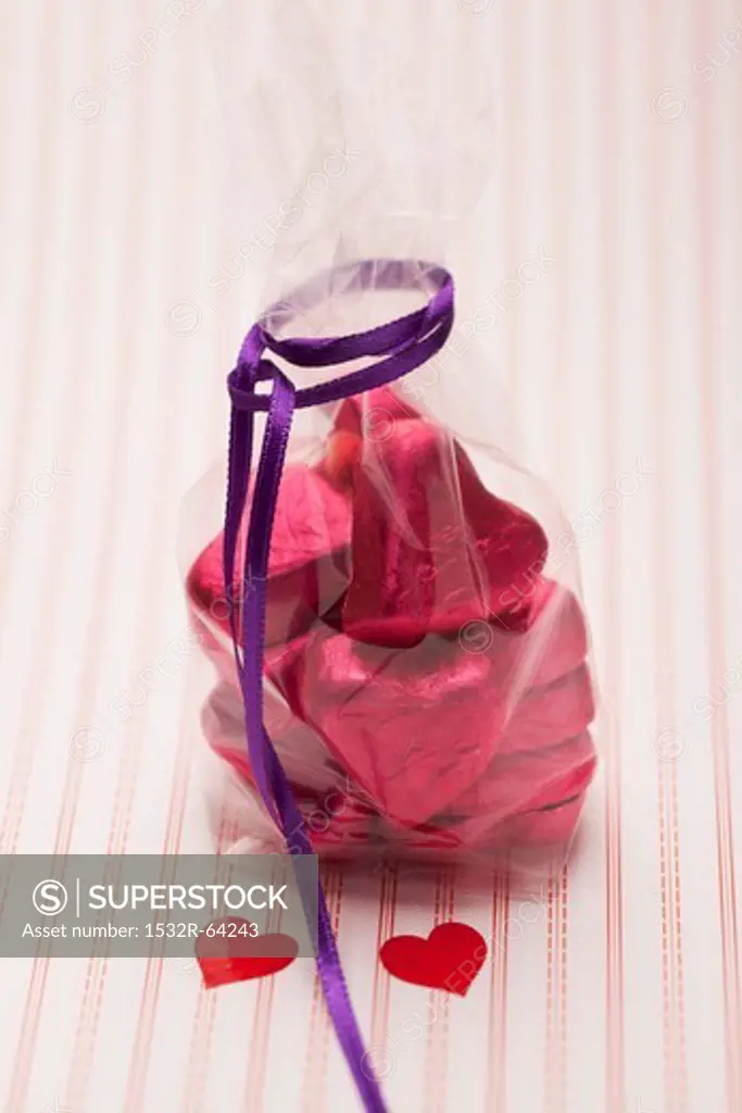 Heart-shaped chocolates wrapped in red foil in a cellophane bag