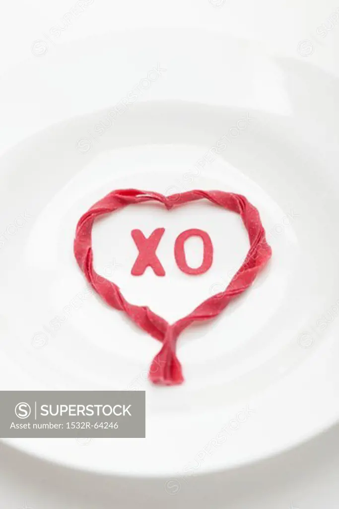 White plate with heart made of red pasta