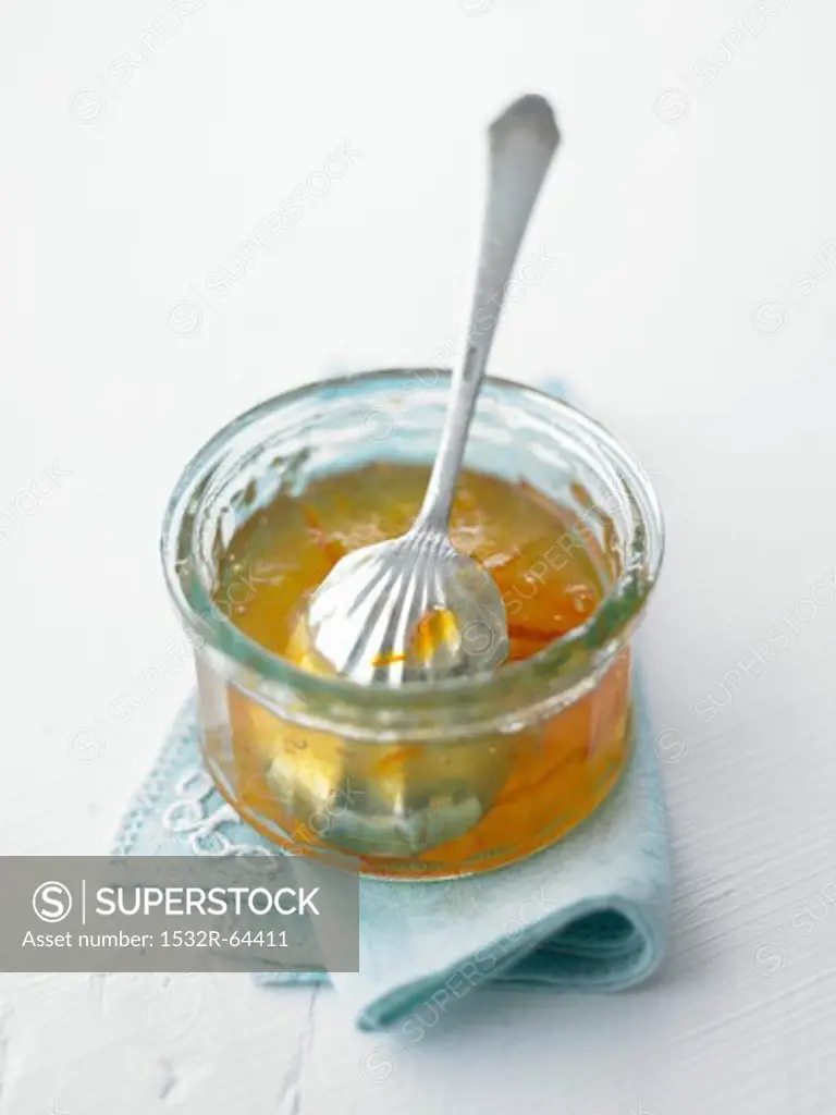 Orange marmalade in a glass dish with a spoon