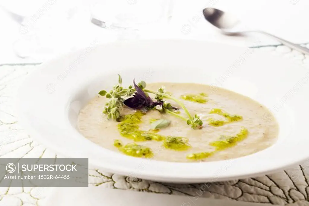 Bowl of Creamy Artichoke Soup with Pesto and Fresh Purple Basil and Lemon Basil