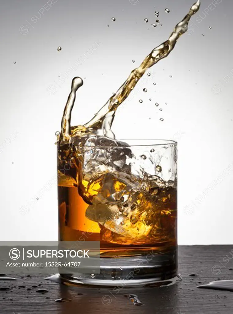 Ice cube falling into whisky glass