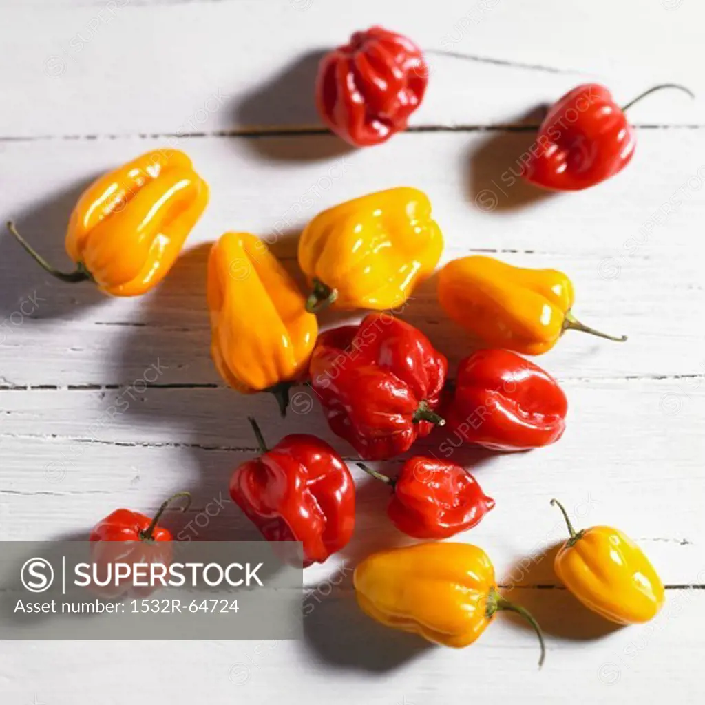 Red and yellow mini peppers on a white wood surface (top view)